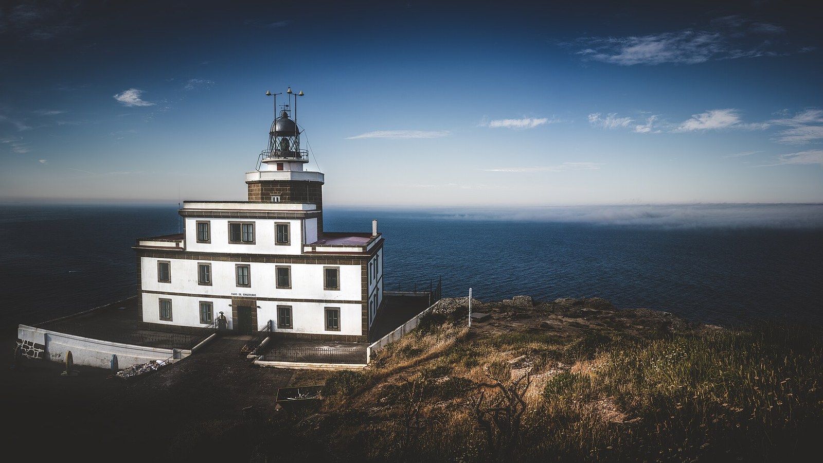 El faro de Finisterre al atardecer sobre el acantilado
