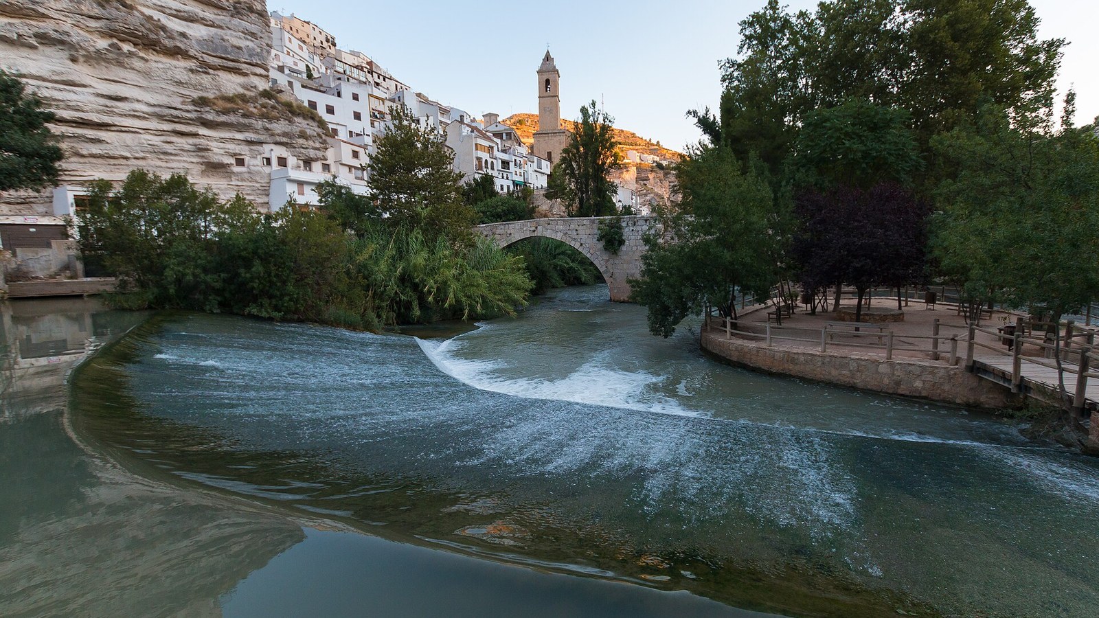 El río Júcar a su paso por Alcalá, con el puente de piedra y el pueblo bajo la roca