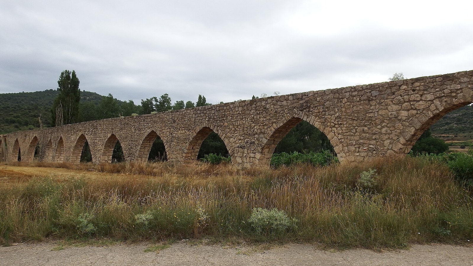 El acueducto de Los Arcos de Alpuente, con su larga hilera de arcos apuntados sobre los campos
