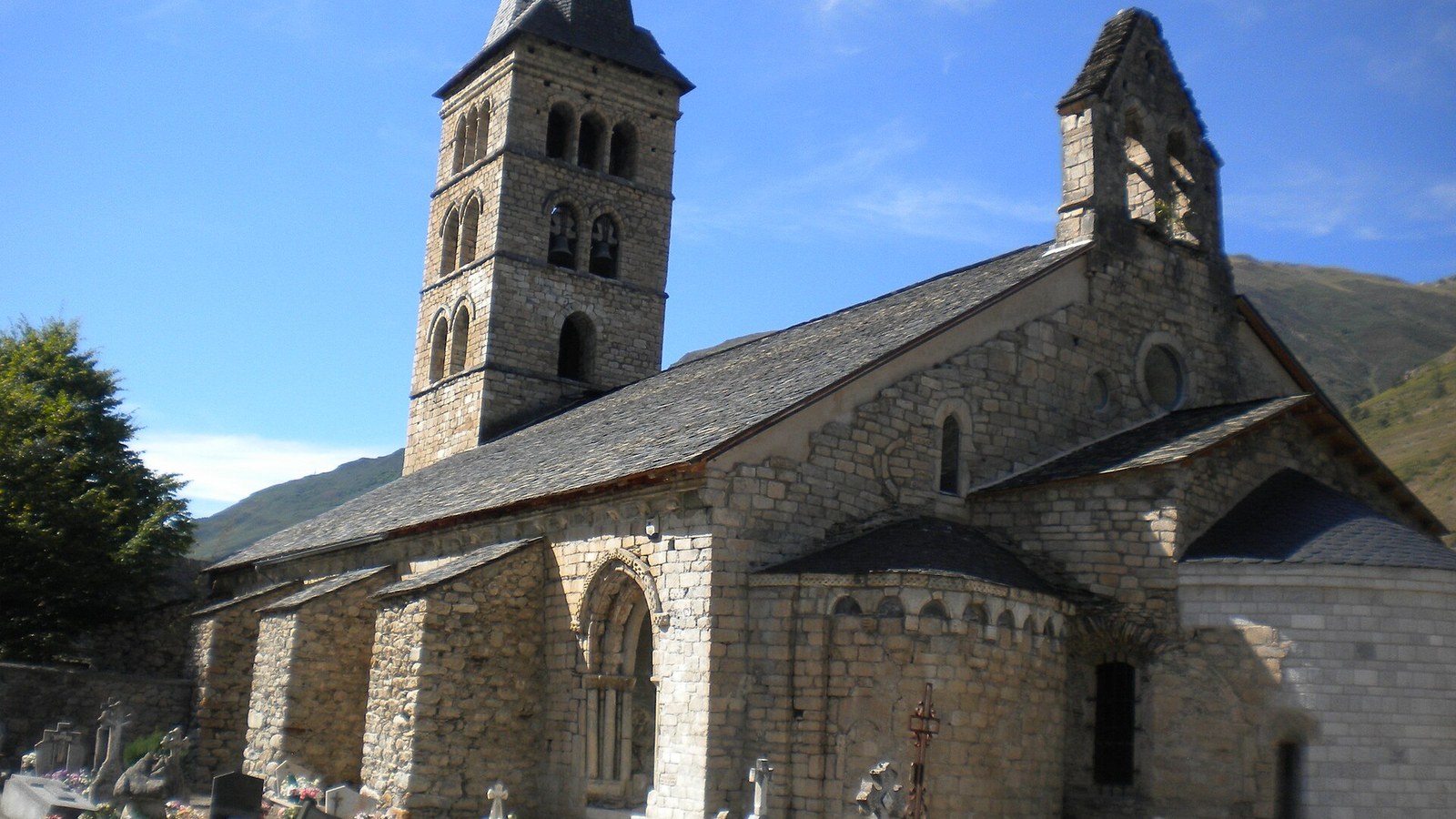 La iglesia románica de Santa María de Arties con su torre y el cementerio delante