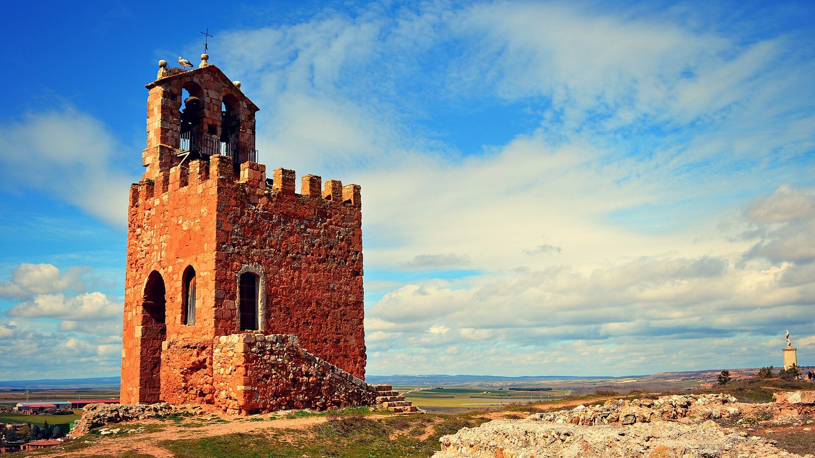 Torre de arenisca roja almenada sobre el cerro de Ayllón, recortada contra el cielo