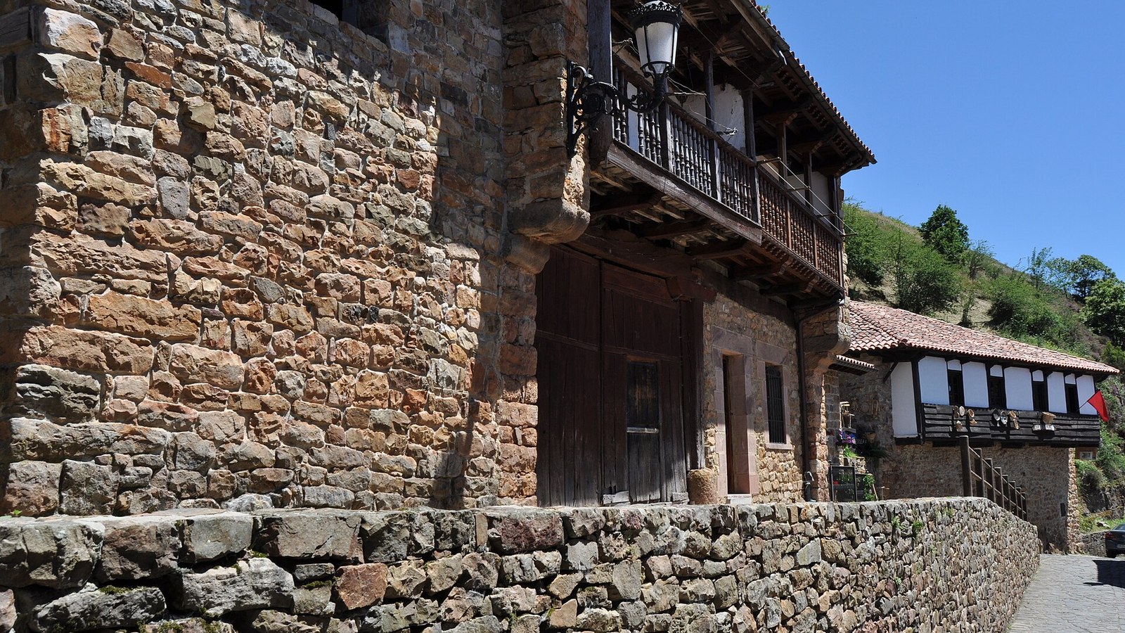 Calle empedrada de Bárcena Mayor entre muros de piedra y casas con solana