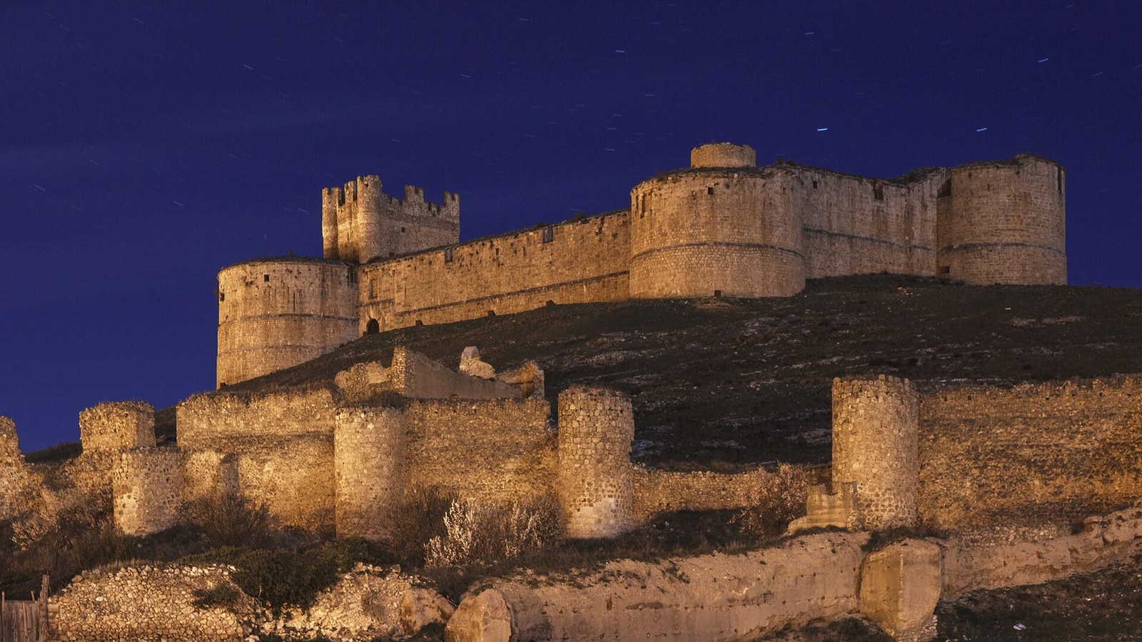 El castillo de Berlanga de Duero iluminado al anochecer sobre su cerro