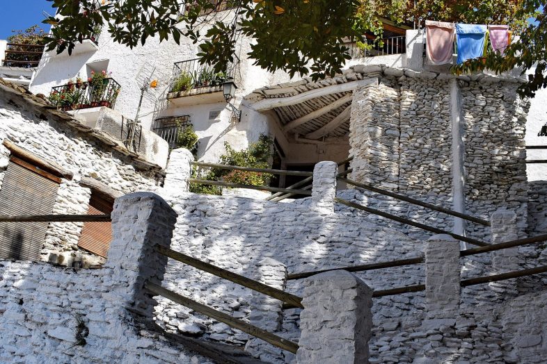 Casas encaladas escalonadas con tinaos y muros de piedra en Capileira