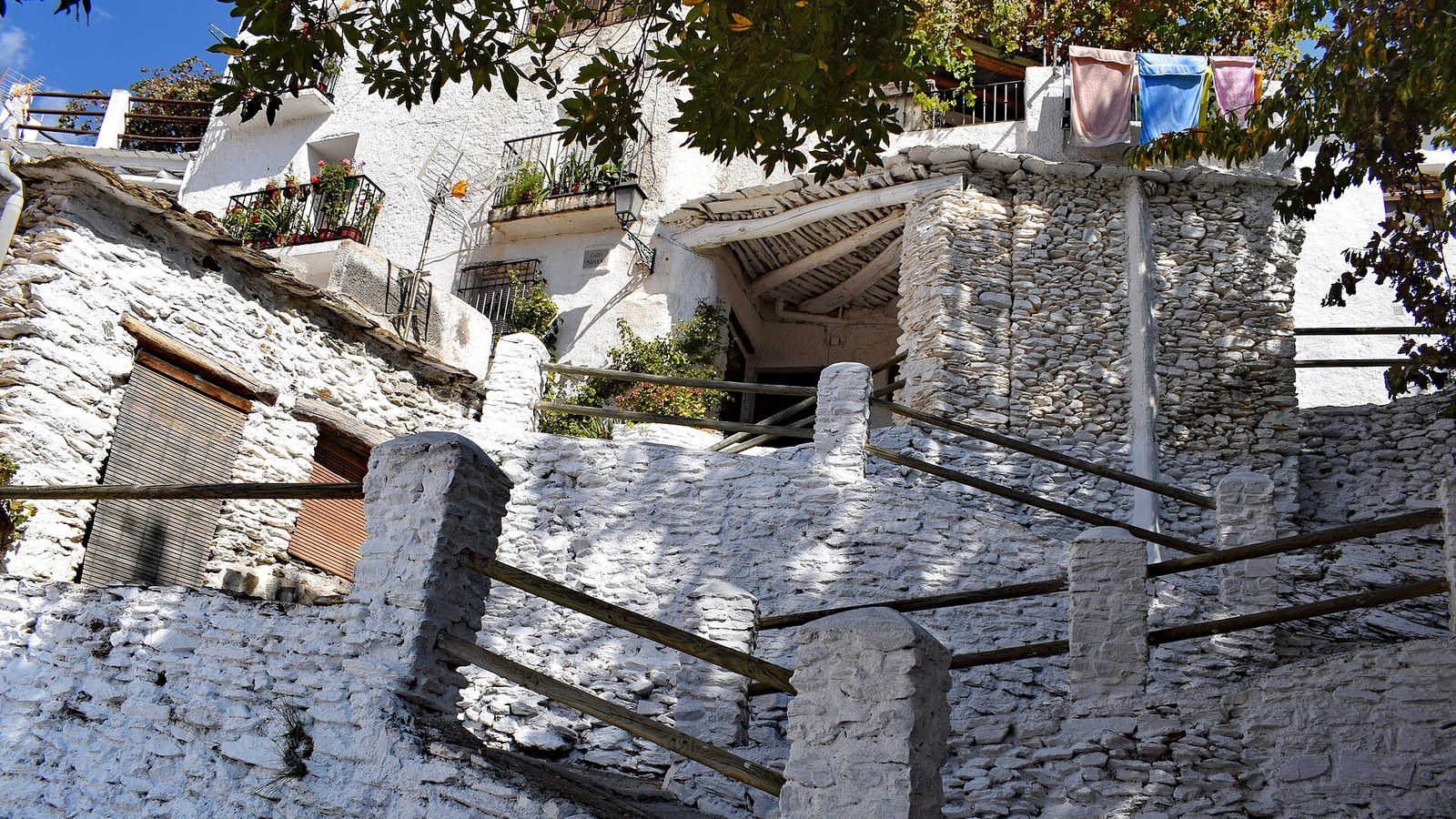 Casas encaladas escalonadas con tinaos y muros de piedra en Capileira