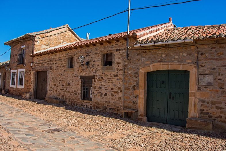 Calle empedrada de Castrillo de los Polvazares con las casas de piedra rojiza y las puertas verdes