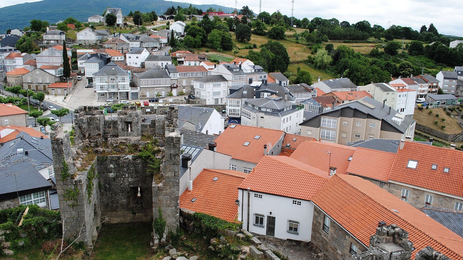 La villa de Castro Caldelas vista desde el castillo, con los tejados y la sierra al fondo