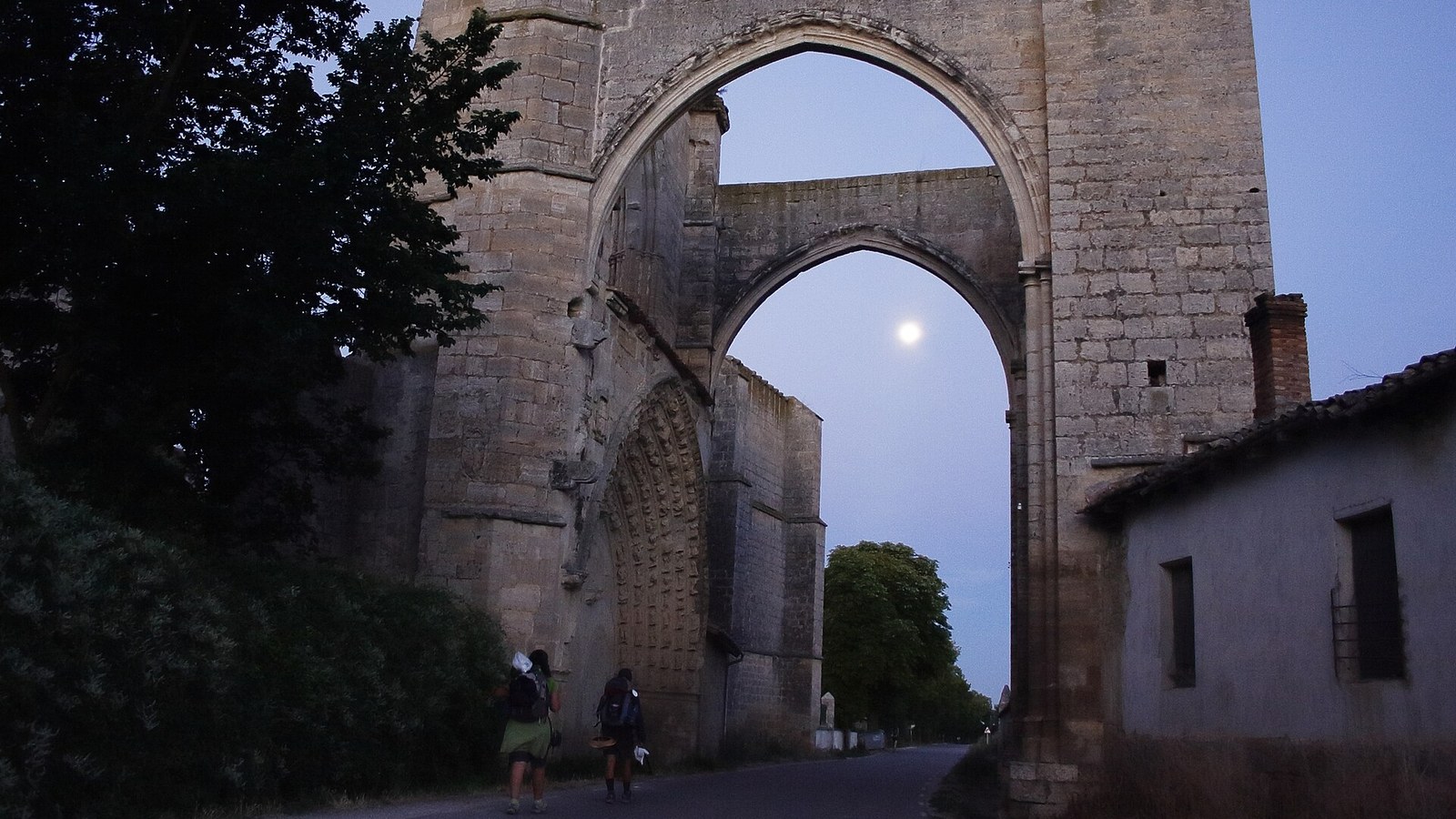 El arco del convento de San Antón sobre la carretera, con peregrinos pasando debajo