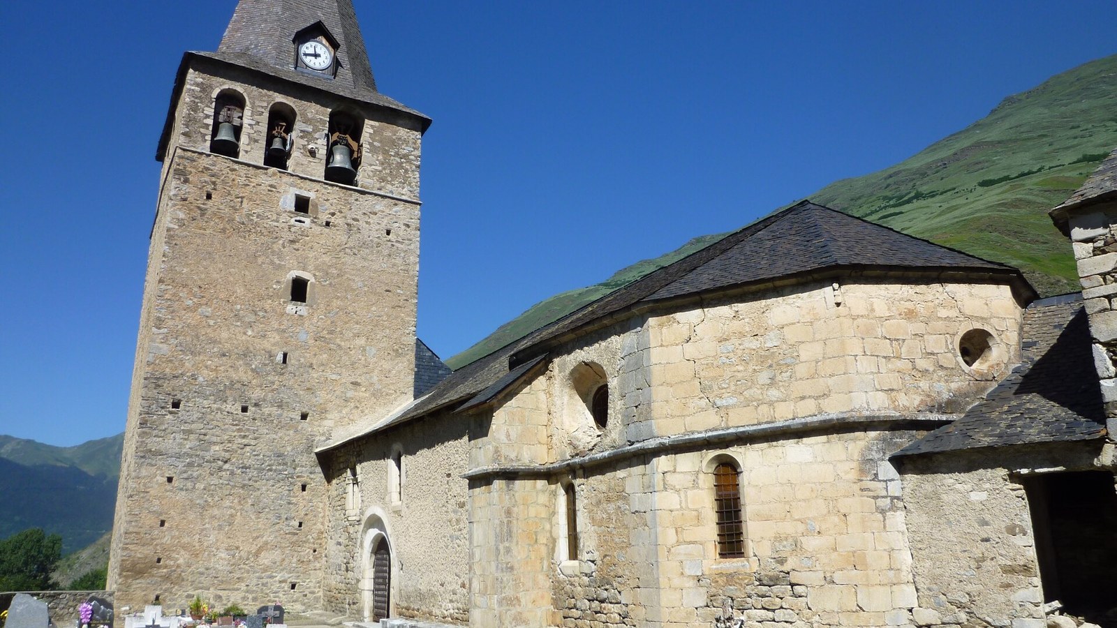 La iglesia de San Julian de Garos con su campanario ancho y la montana detras