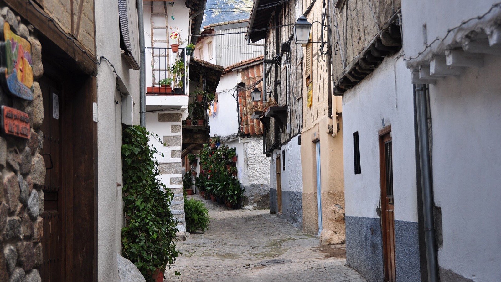 Calle empedrada del barrio judío de Hervás con balcones de madera y macetas