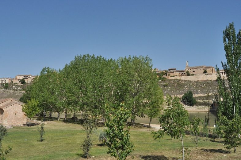 Maderuelo sobre su cerro amurallado, visto desde las praderas junto al embalse de Linares