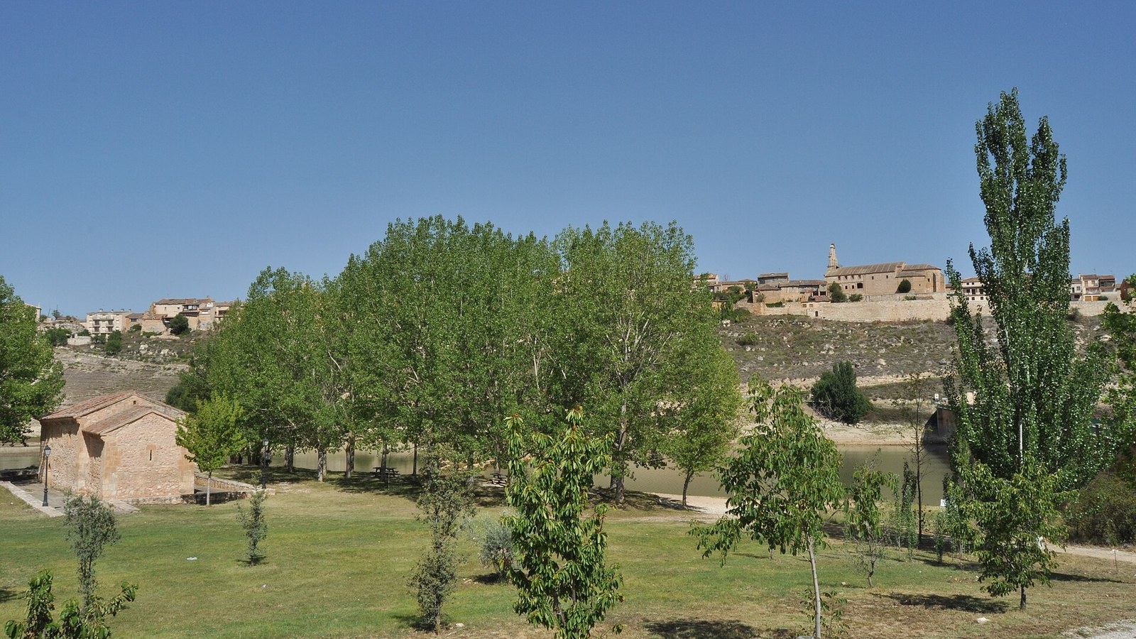 Maderuelo sobre su cerro amurallado, visto desde las praderas junto al embalse de Linares