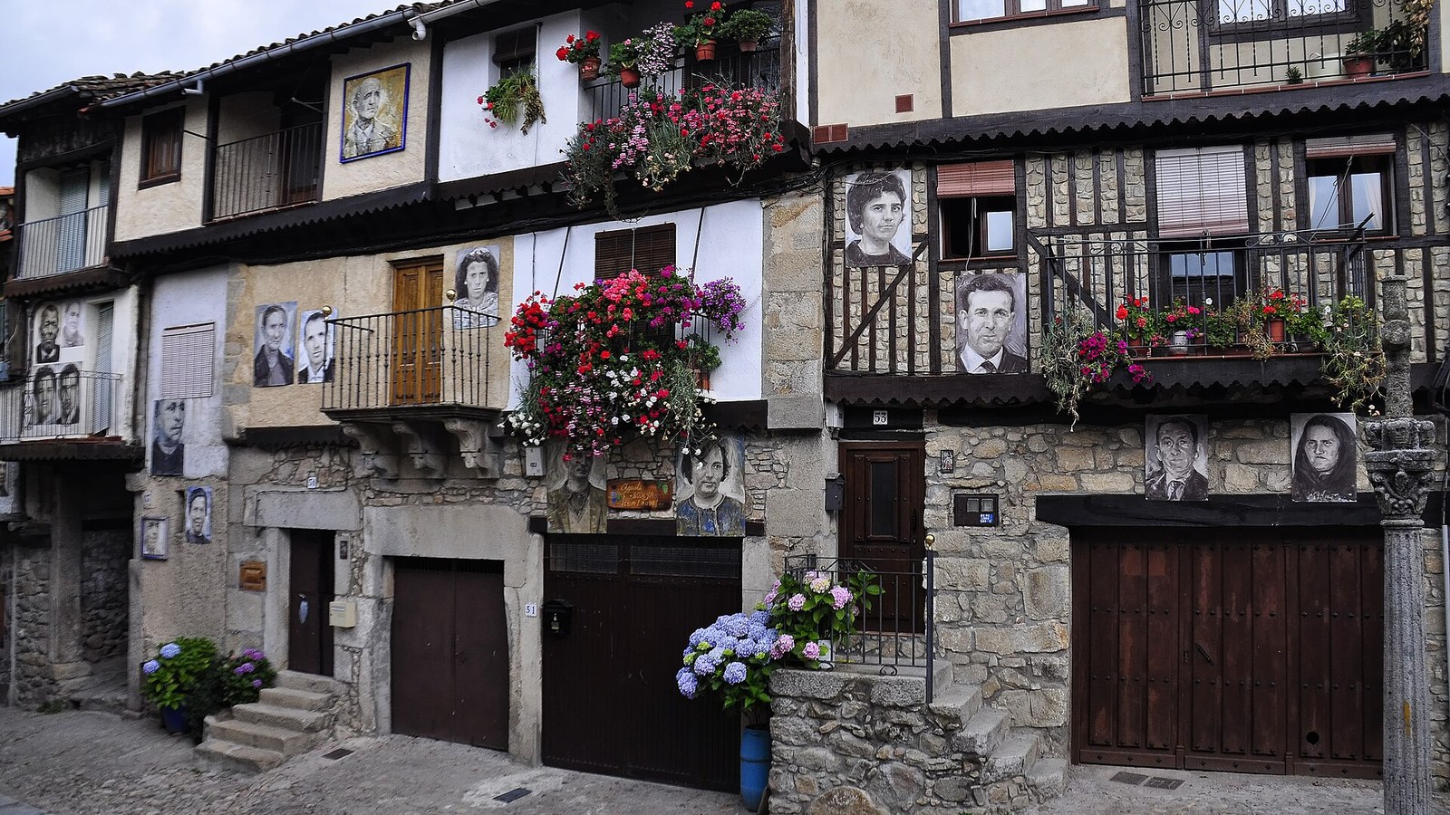 Fachada de Mogarraz cubierta de retratos pintados de vecinos, entre balcones de madera y flores