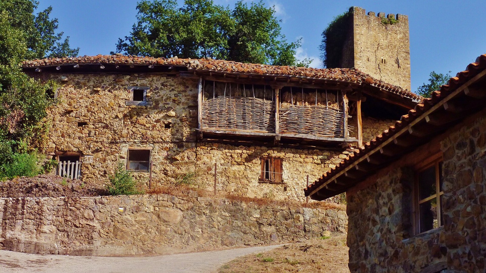 Casona de piedra de Mogrovejo con galería de madera y la torre medieval al fondo