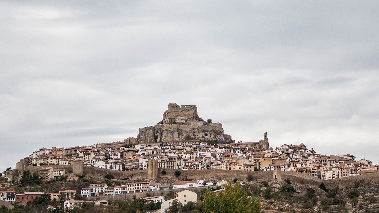 Morella amurallada sobre su muela, con el castillo en lo más alto y el caserío en la ladera