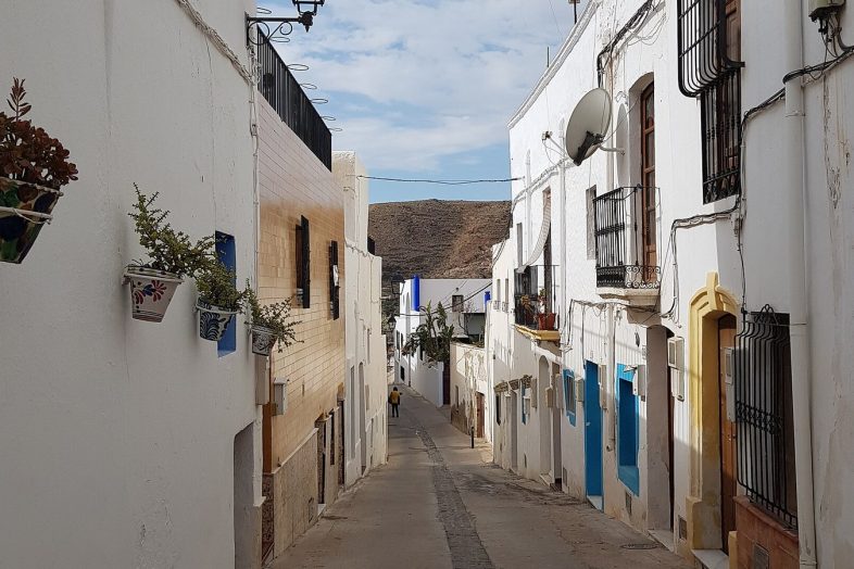 Calle encalada de Níjar con macetas colgadas en las fachadas y la sierra al fondo