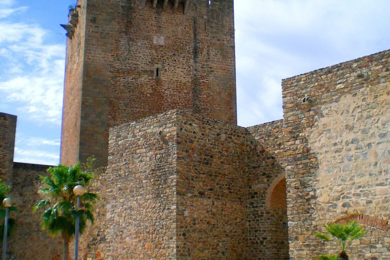 La torre del homenaje y las murallas del castillo de Olivenza entre palmeras