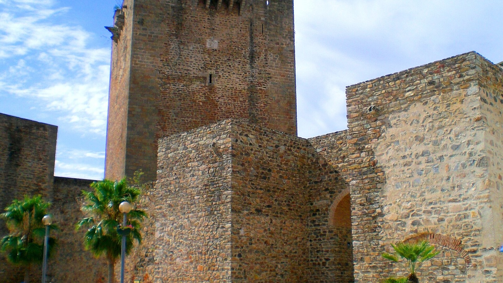 La torre del homenaje y las murallas del castillo de Olivenza entre palmeras