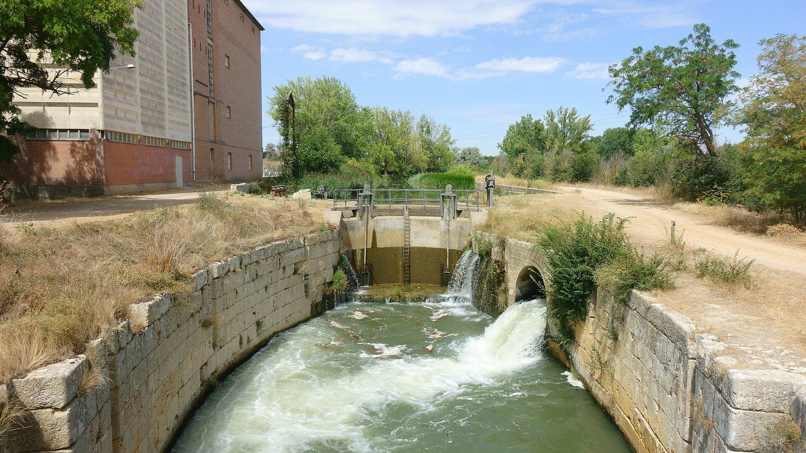 Una esclusa del Canal de Castilla con el agua saltando entre los muros de sillería