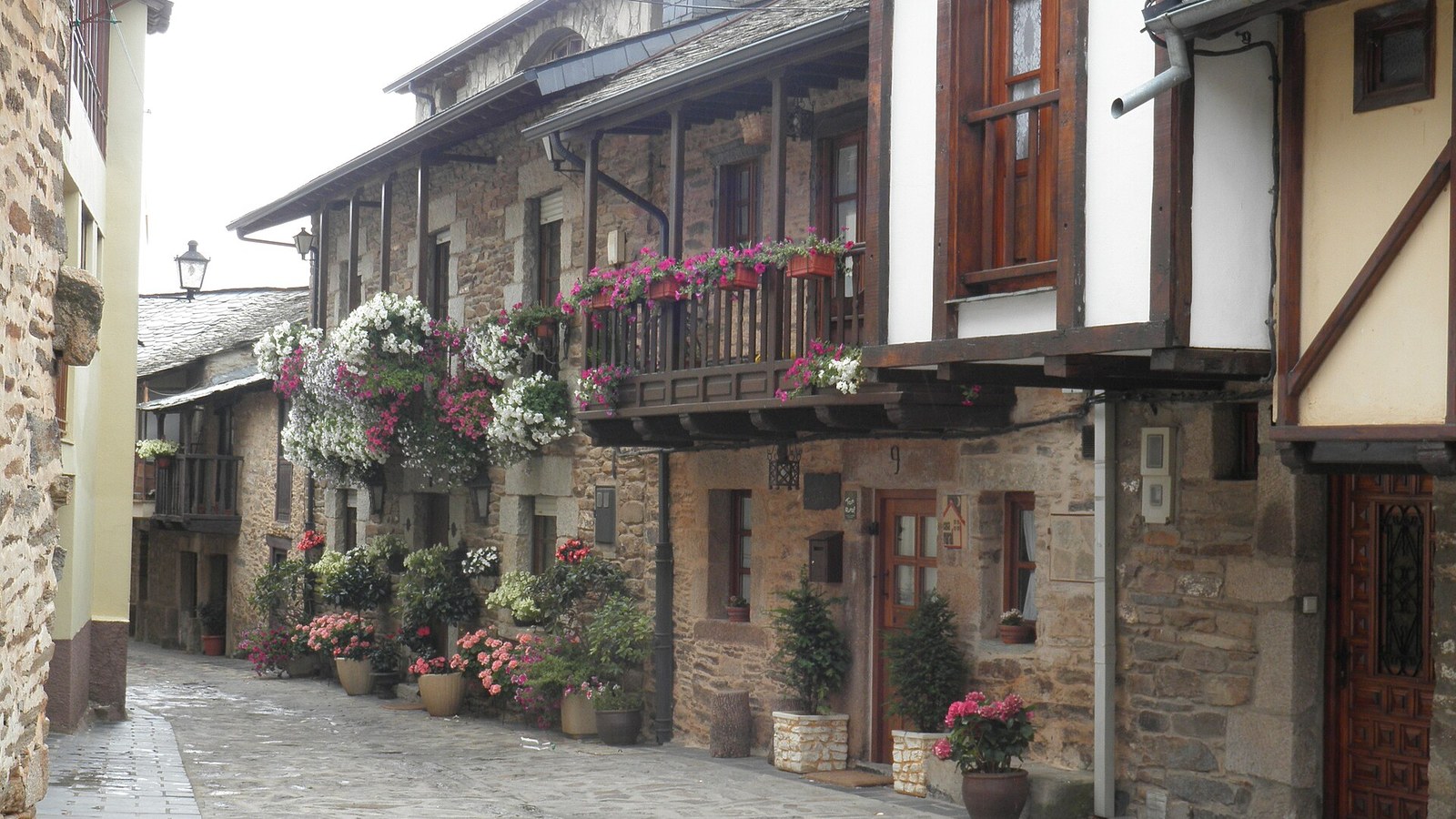 Calle empedrada de Puebla de Sanabria con casas de piedra y balcones de madera con flores