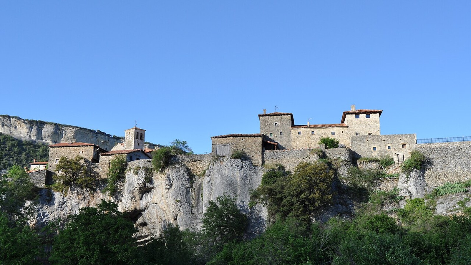 El caserío de Puentedey sobre la roca, con la torre de los Brizuela, contra el cielo azul