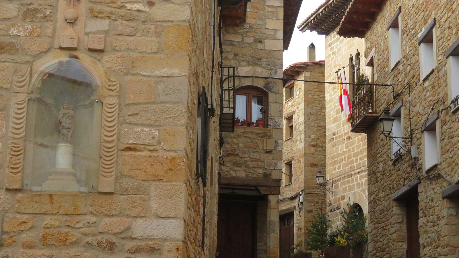 Calle Mayor de Puertomingalvo con una hornacina de piedra y balcones de forja
