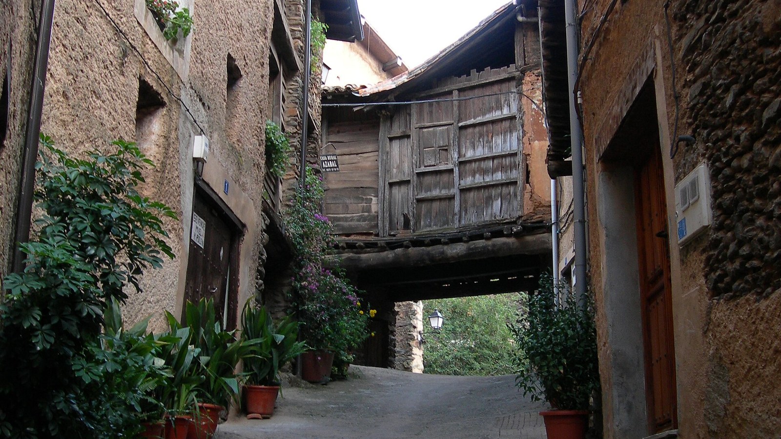 Calle estrecha de Robledillo de Gata con balcones de madera y un pasadizo cubierto