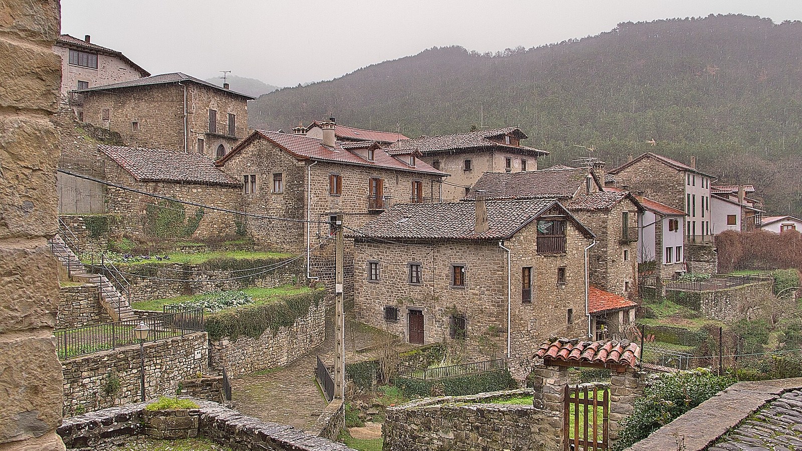Casas de piedra con tejados rojos y huertos en cuesta en la villa de Roncal