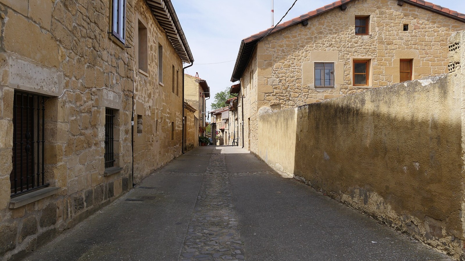 Calle empedrada de Sajazarra entre casas de piedra dorada