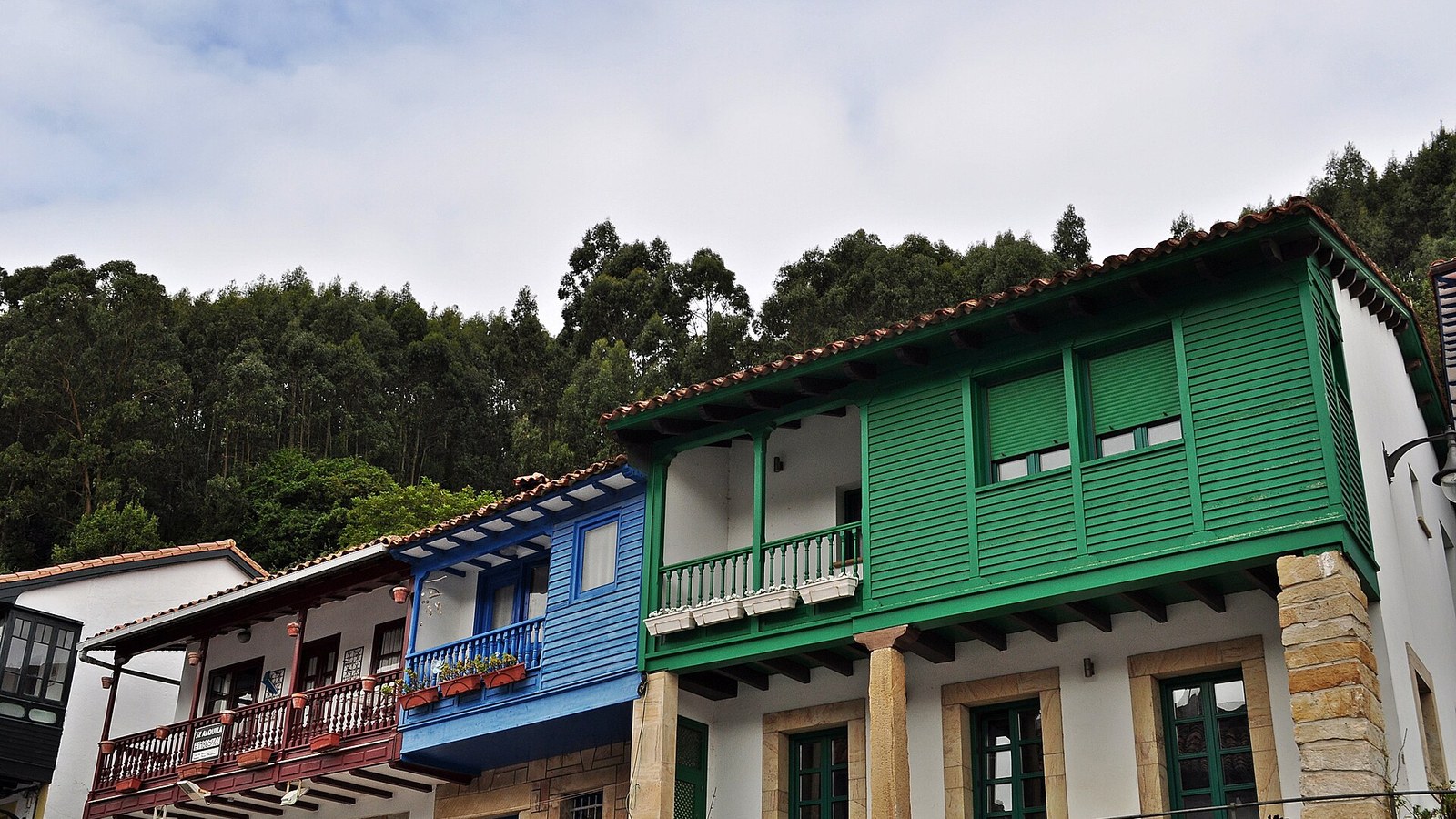 Galerías de madera pintadas de verde, azul y rojo en las casas de Tazones