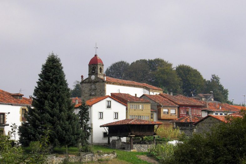 Torazo con su iglesia, las casas blancas y un hórreo entre los prados de Cabranes