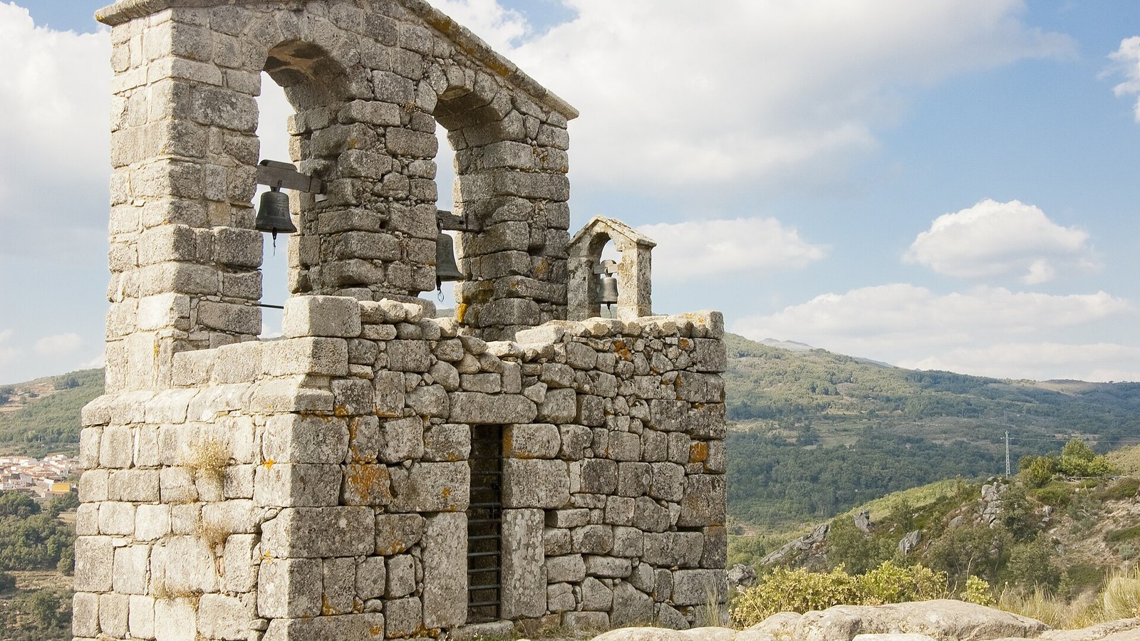 Espadaña de granito de la iglesia de San Juan de Trevejo recortada contra el cielo