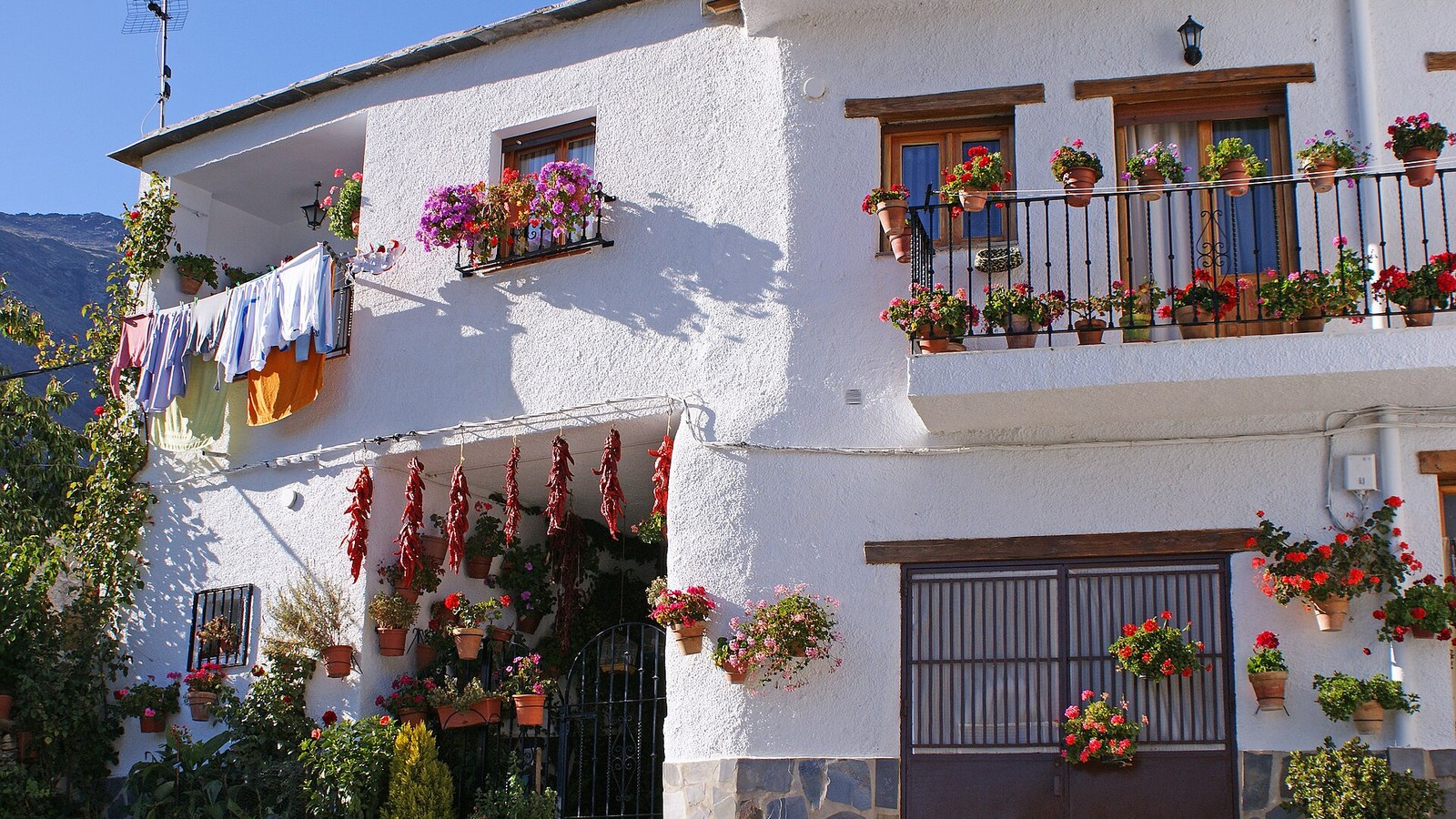 Casa encalada de Trevélez con geranios, pimientos secándose y ropa tendida