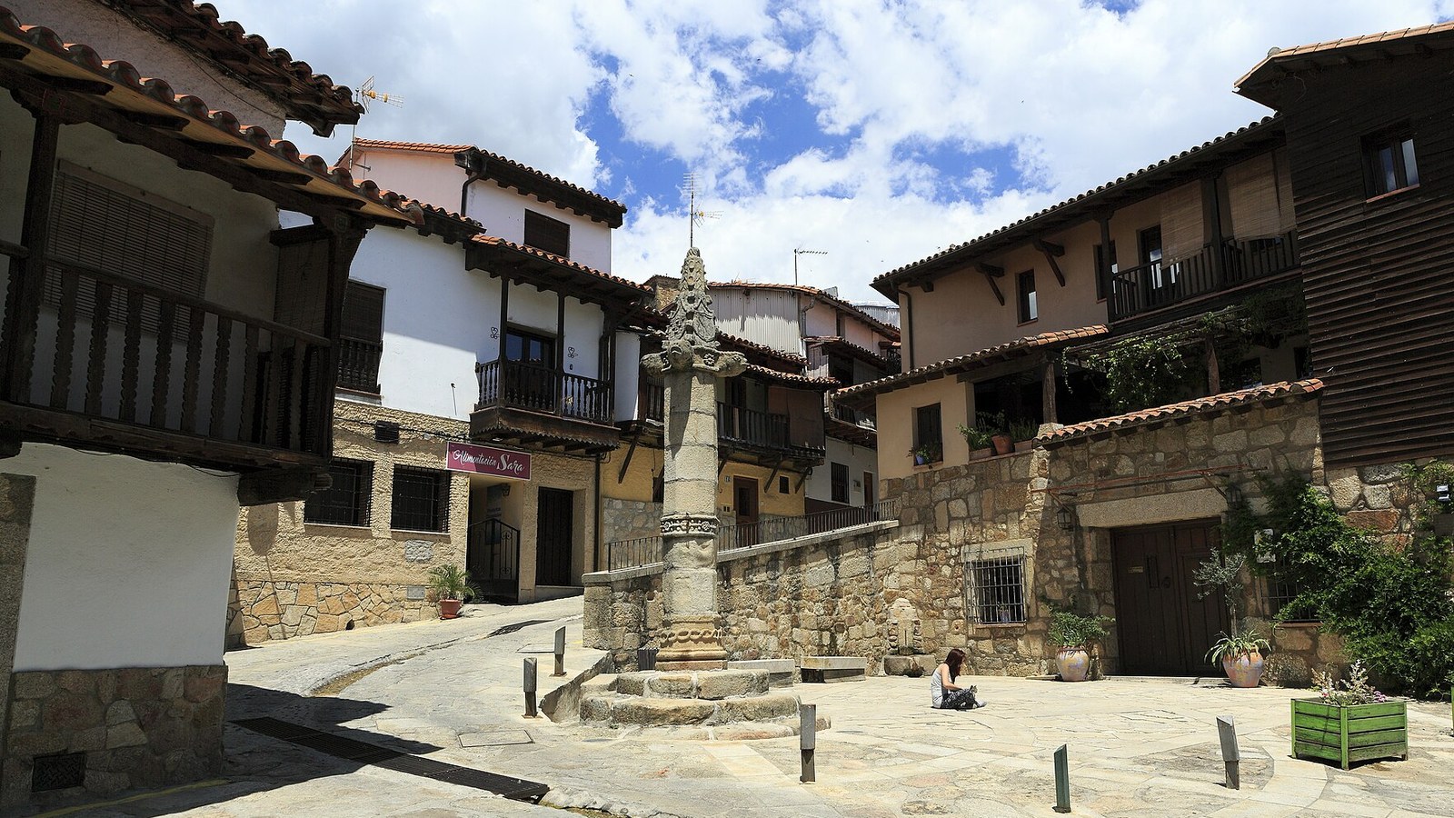 La picota gótica de Valverde de la Vera en su plaza, rodeada de casas con balconadas de madera