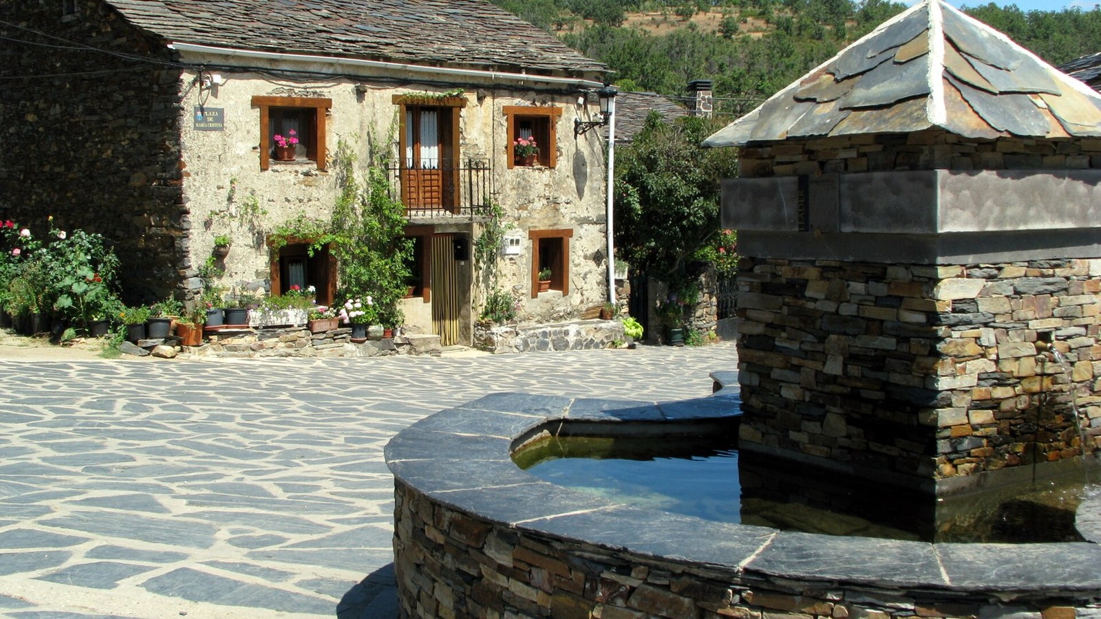 Fuente circular de pizarra con tejadillo cónico en la plaza de Valverde de los Arroyos