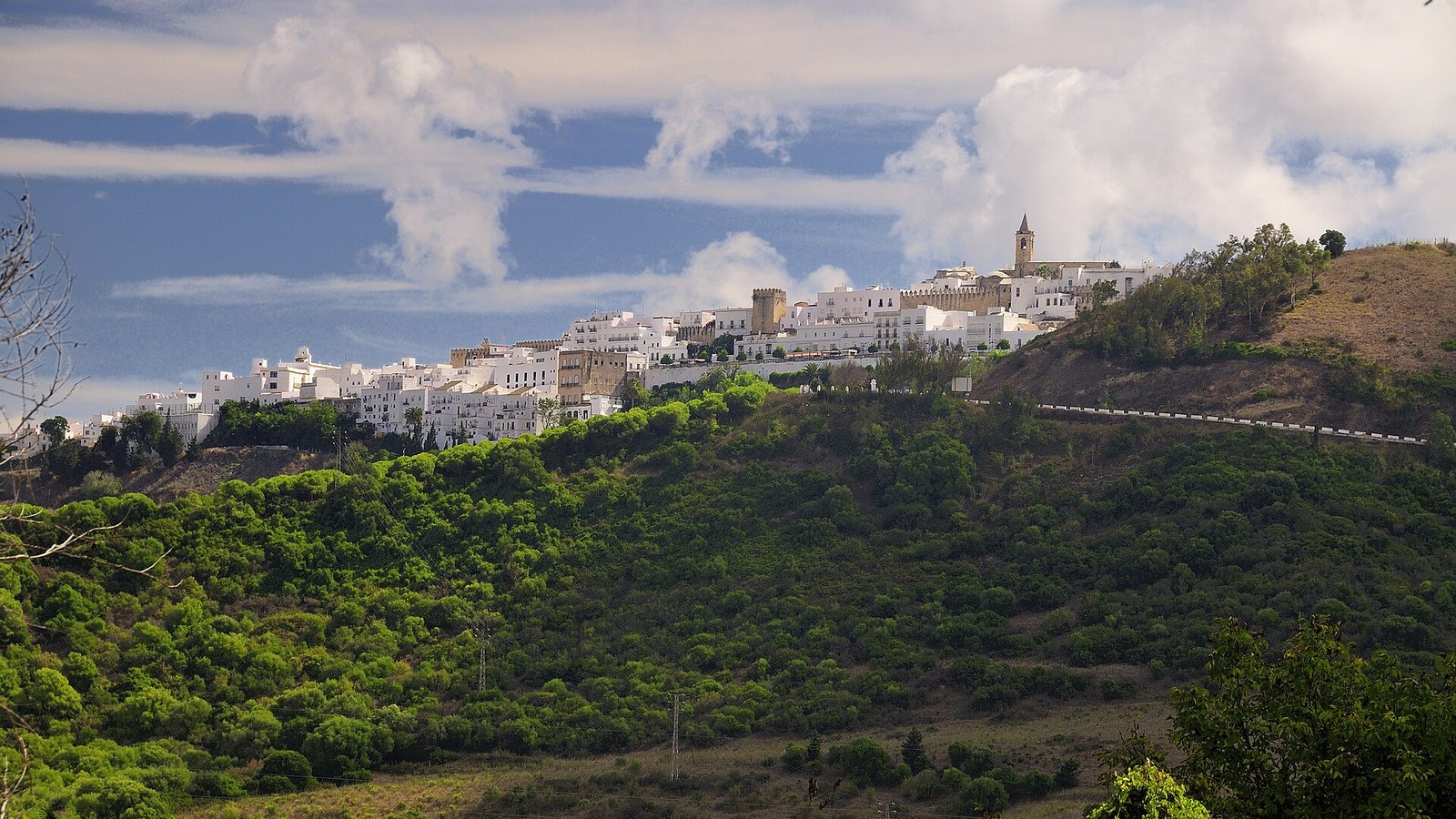 Vejer de la Frontera, blanco sobre su cerro verde, con grandes nubes atlánticas al fondo