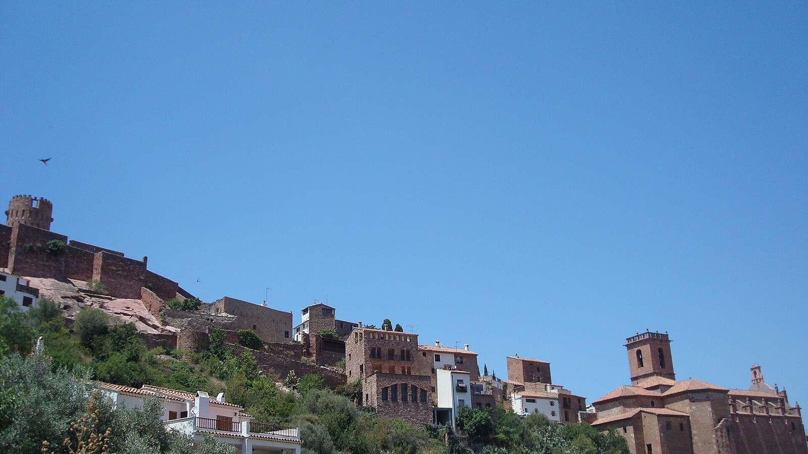Vilafamés con sus casas blancas subiendo hacia el castillo de piedra roja en lo alto
