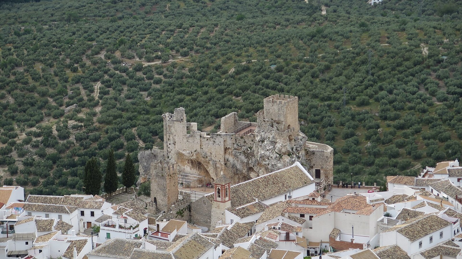 El castillo de Zuheros sobre su roca entre las casas blancas y el mar de olivos de la Subbética